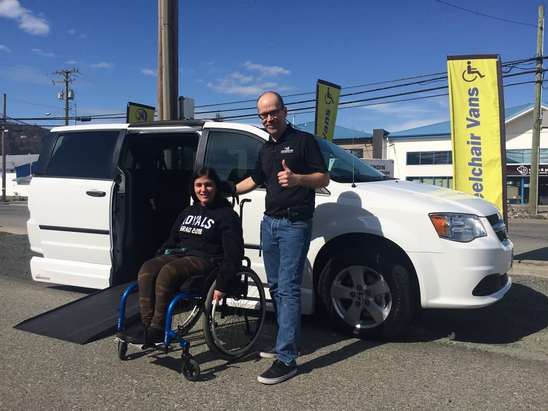 A customer beside their new wheelchair accessible van